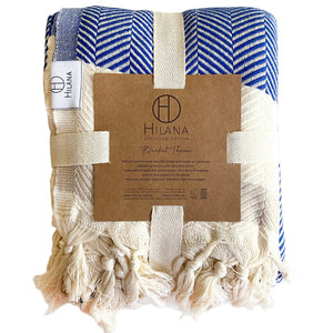 Navy and cream Pipa cotton throw folded with its packaging on a white background