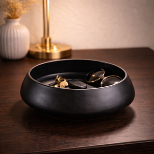 Black low-profile ceramic bowl holding keys on a wooden table