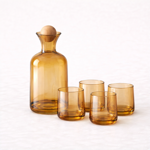Amber glass water carafe and four matching tumblers on a light background