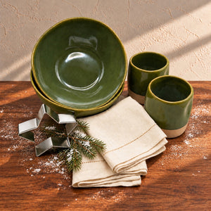 Christmas Breakfast Gift Set for Two with olive-green bowls and cups, ivory napkins and a star cookie cutter, styled with an evergreen sprig and a light dusting of snow