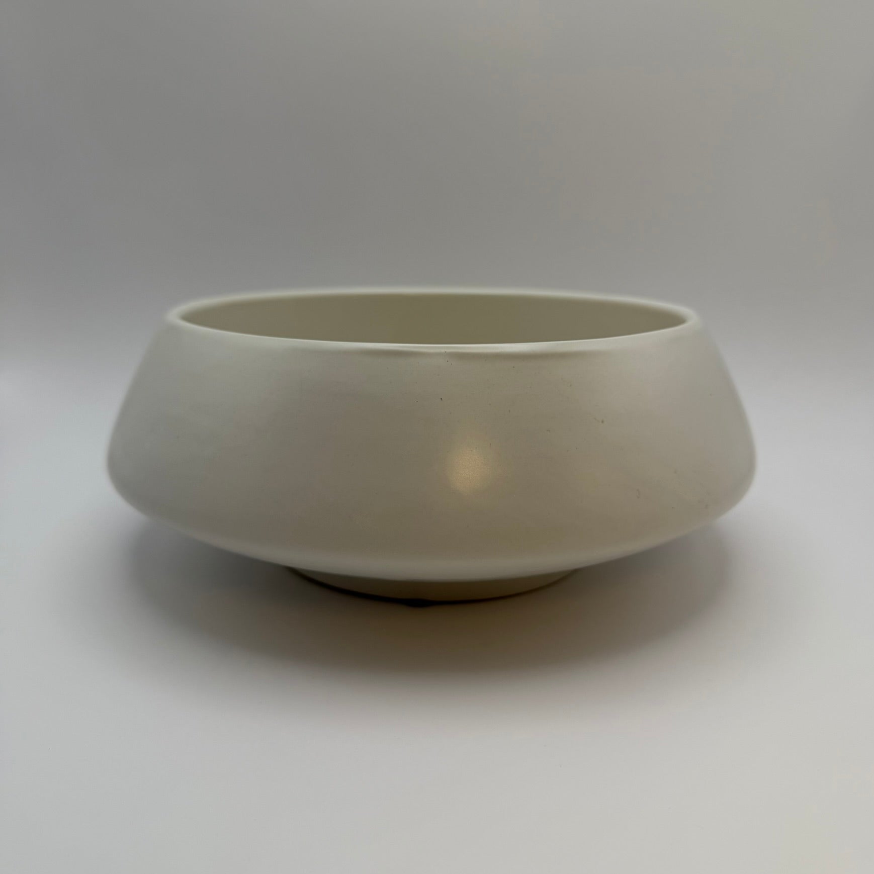 White low-profile ceramic bowl with a small raised base, side view