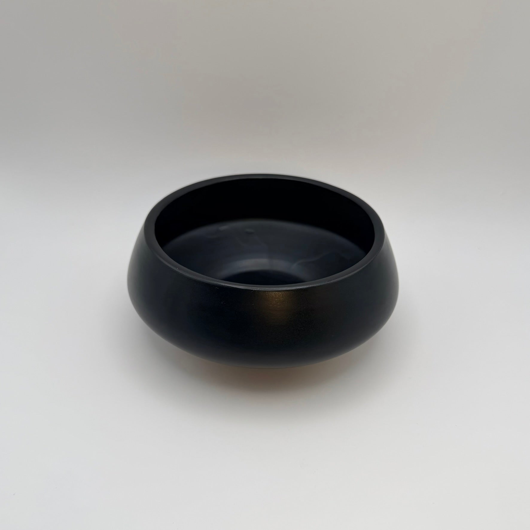 Black low-profile ceramic bowl showing its rounded rim and interior