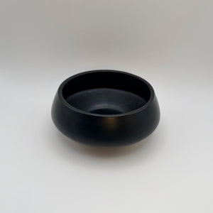 Black low-profile ceramic bowl showing its rounded rim and interior