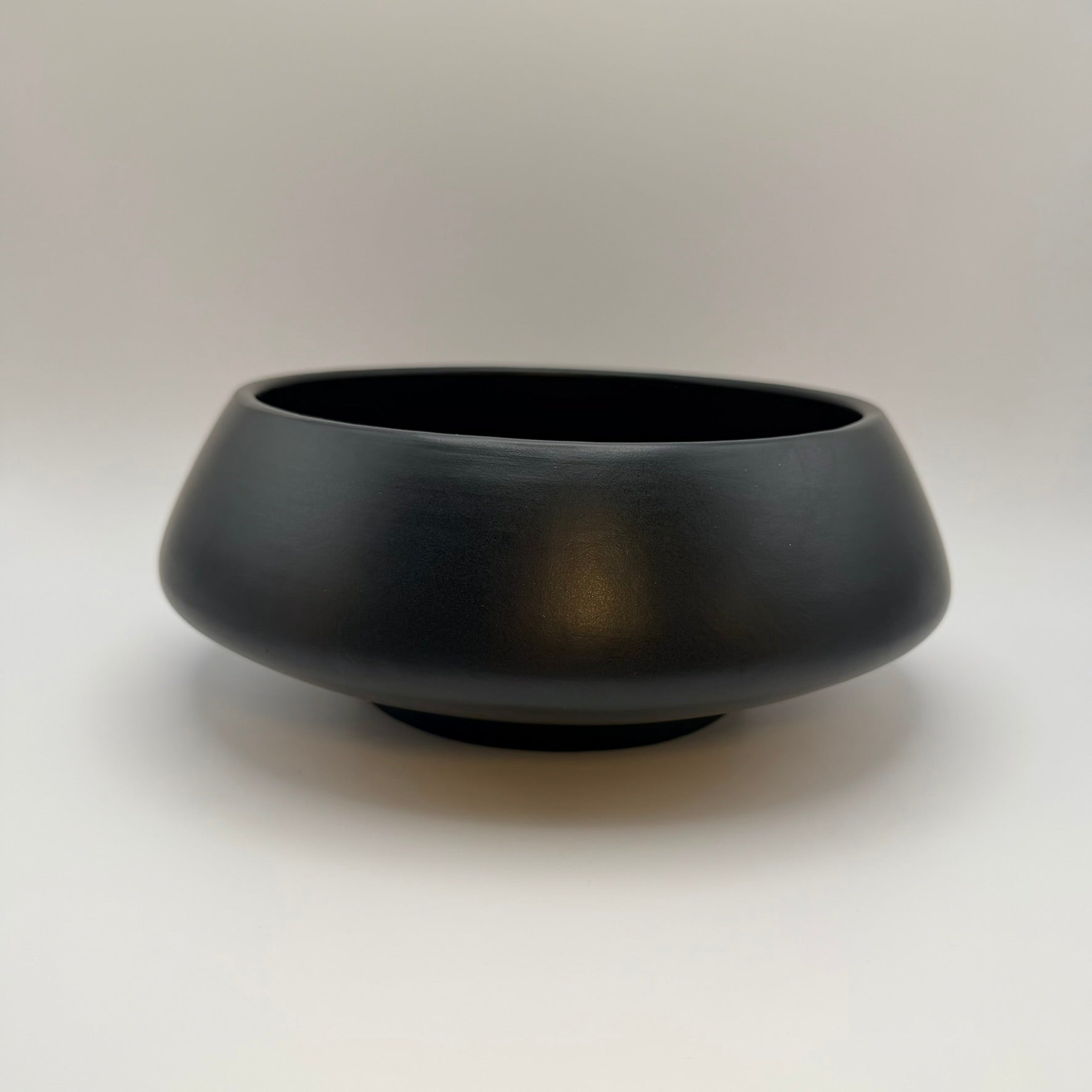 Black low-profile ceramic bowl with a wide opening, front view