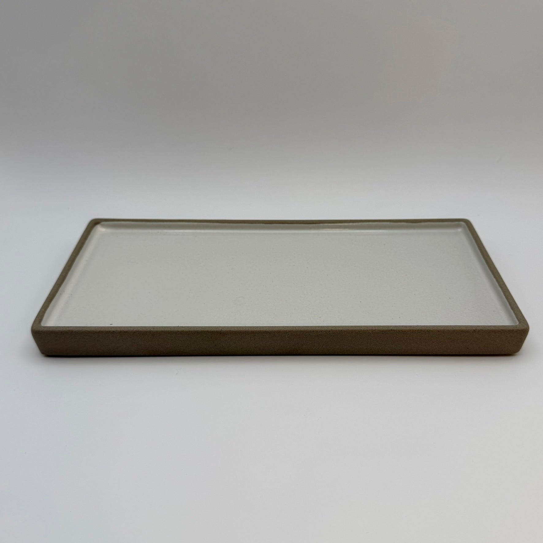 Rectangular ceramic candle tray with a pale centre and dark raised rim