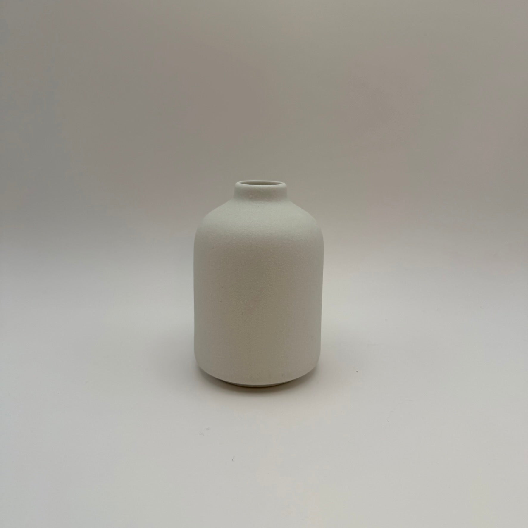 White sand-glazed ceramic bud vase viewed from the front