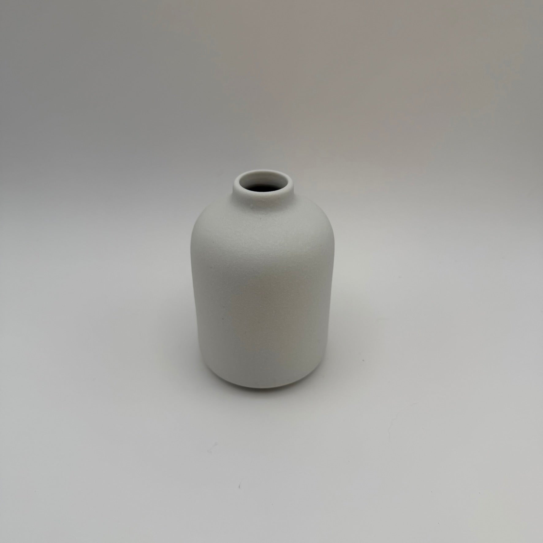 White sand-glazed ceramic bud vase viewed from above