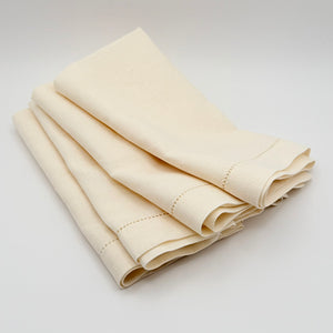 Folded natural linen napkins with stitched borders on a light background