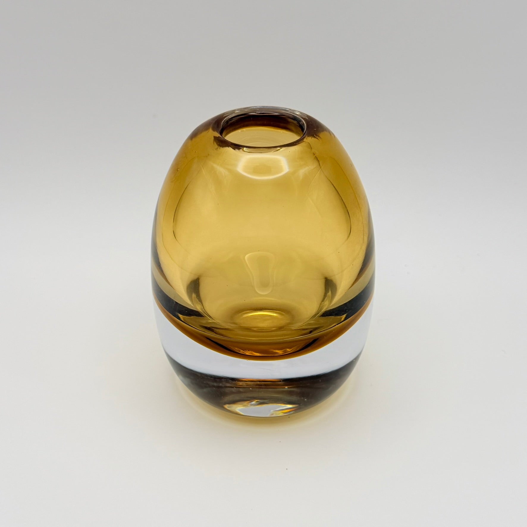 Small rounded amber glass bud vase on a light background