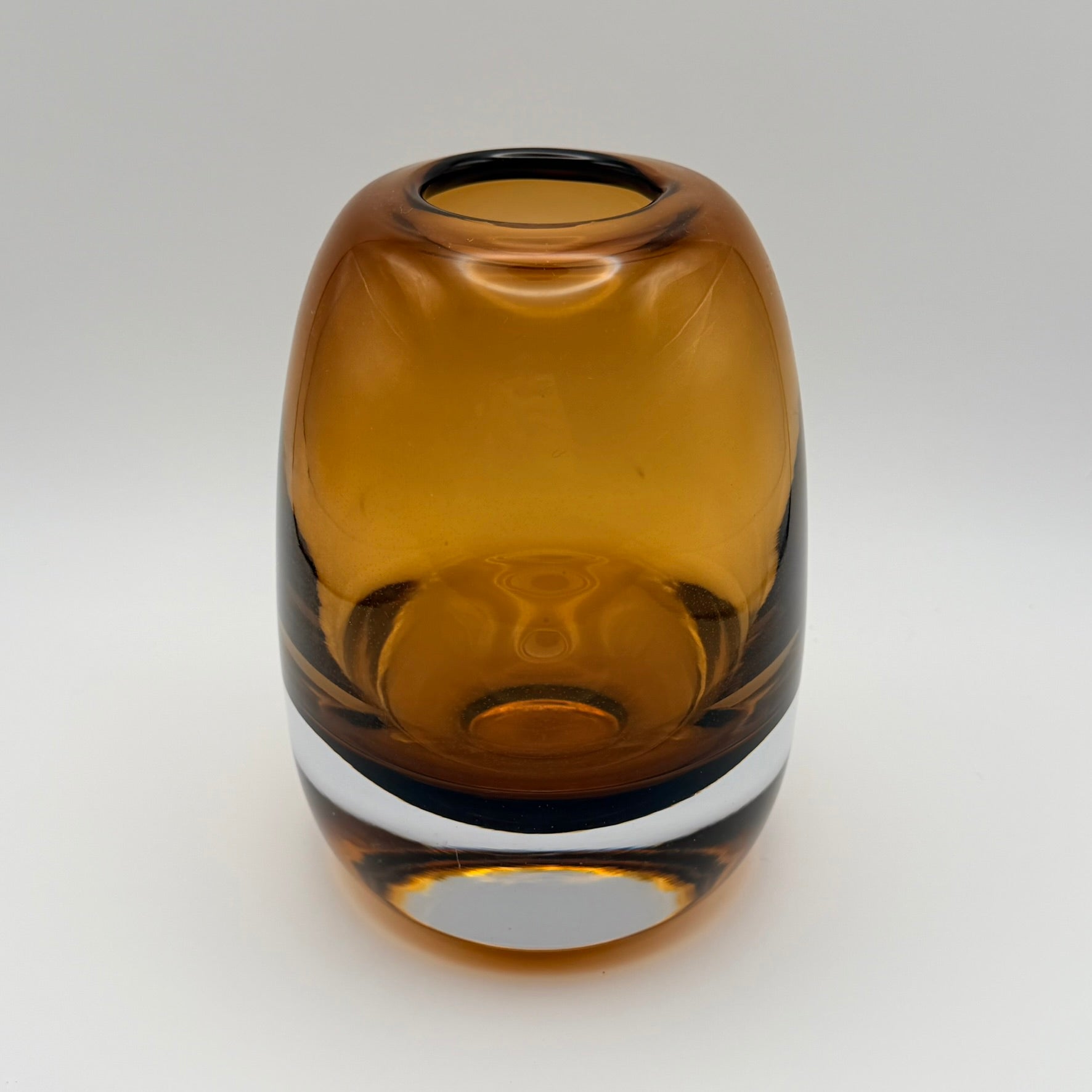Large amber glass bud vase viewed from above on a light background