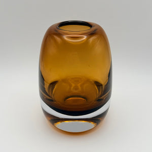 Large amber glass bud vase viewed from above on a light background