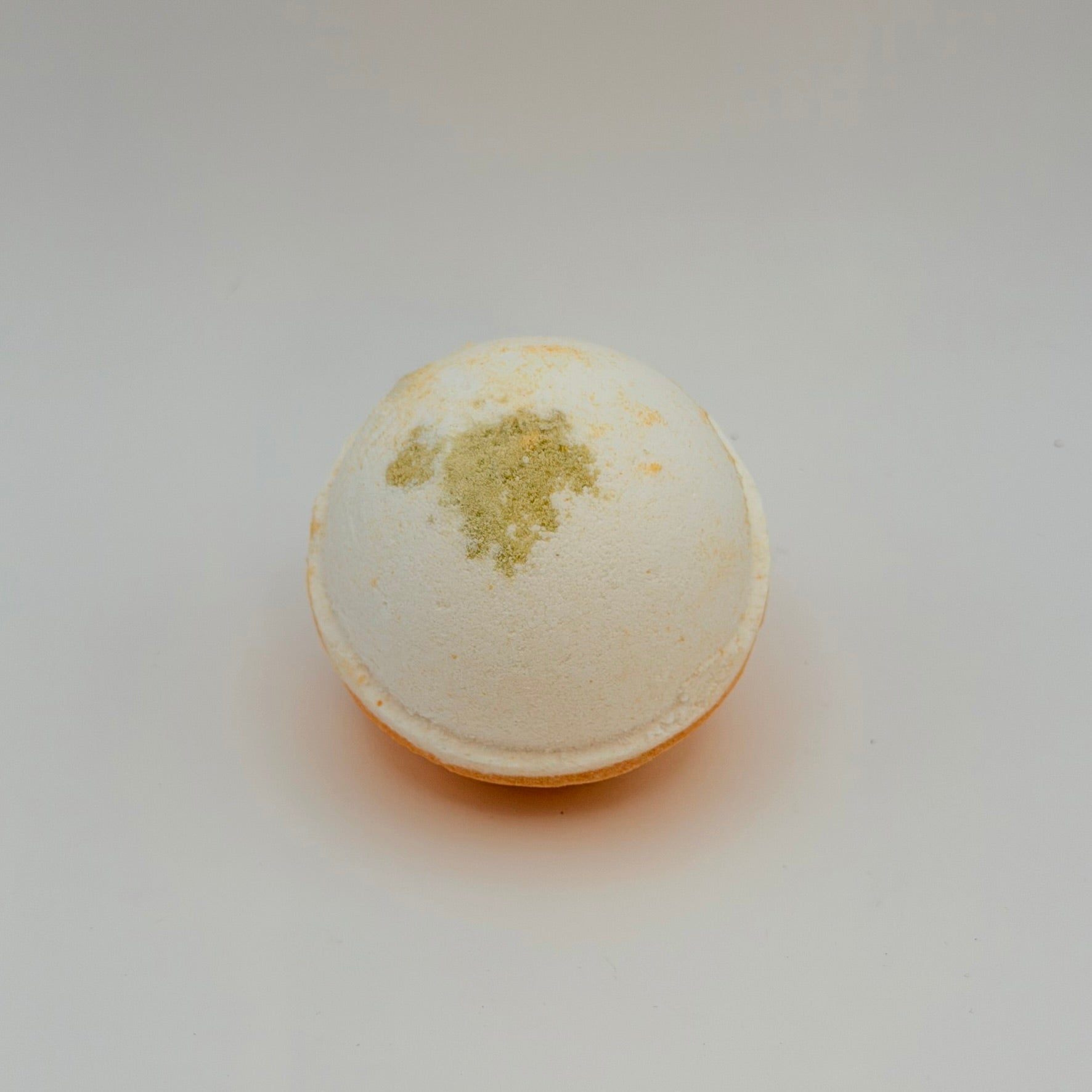 Round cream bath bomb topped with dried botanicals