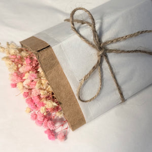 Gift parcel wrapped in white paper and twine with a small dried posy
