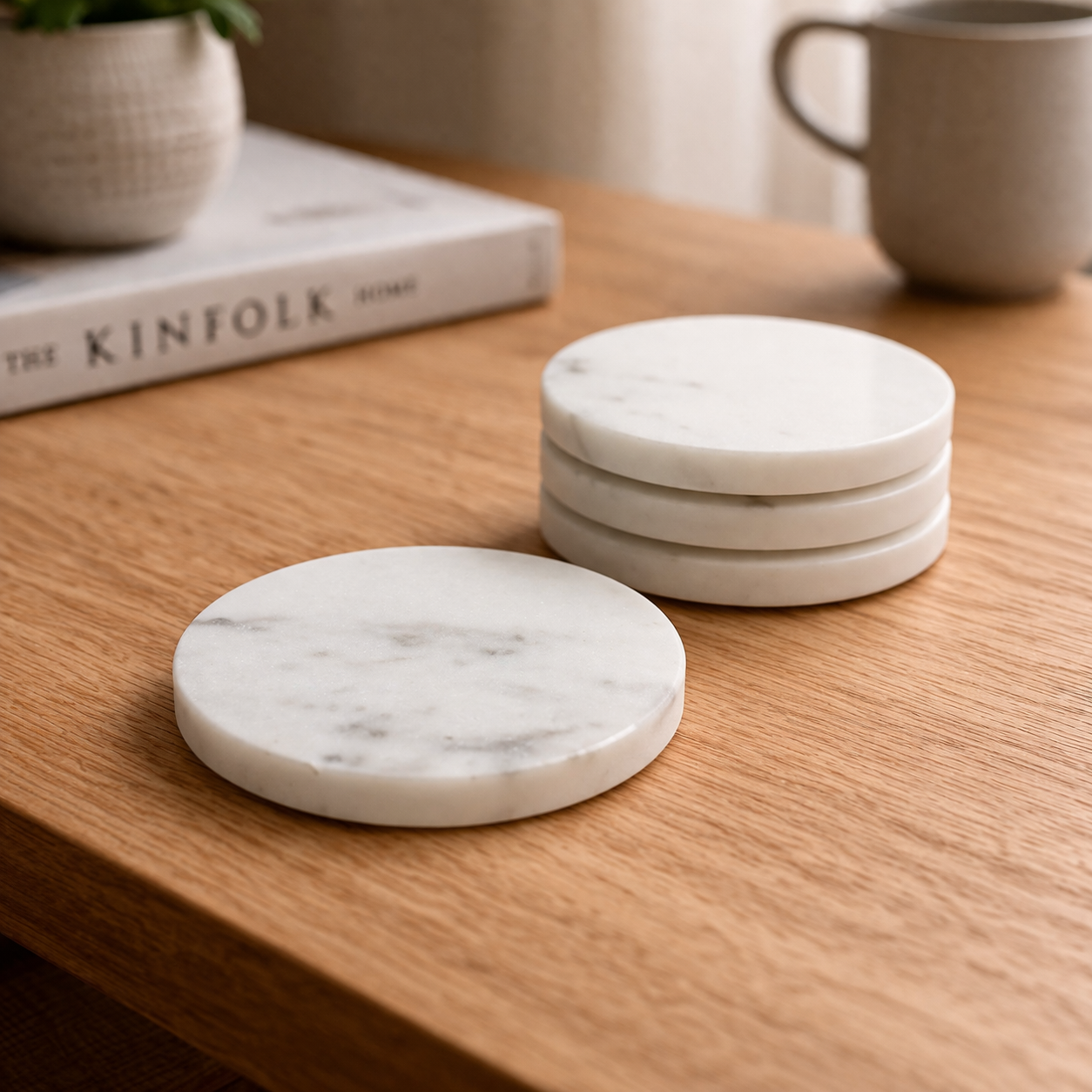 Four round white marble coasters on a wooden table