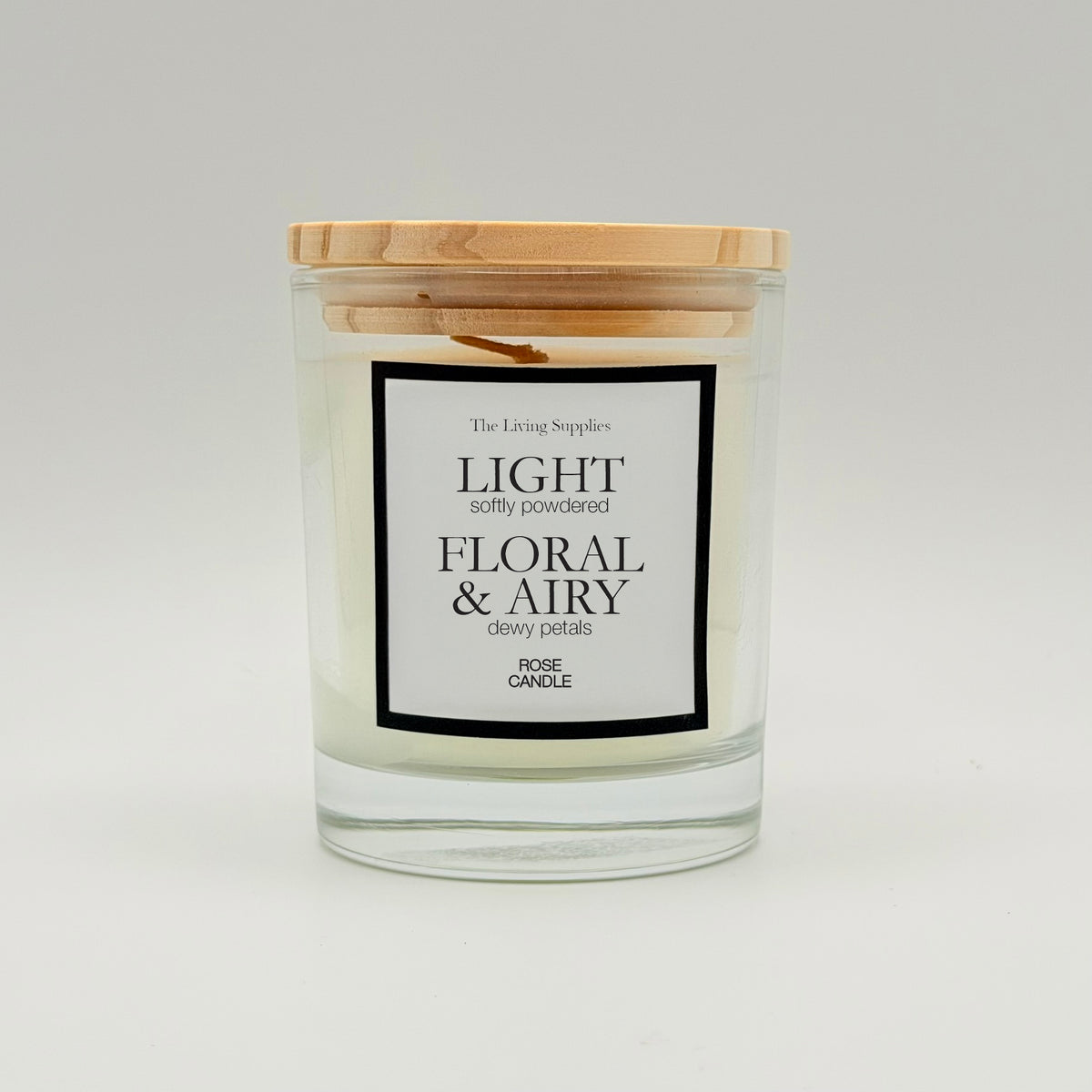Rose candle in a clear glass jar with a wooden lid and black-bordered label