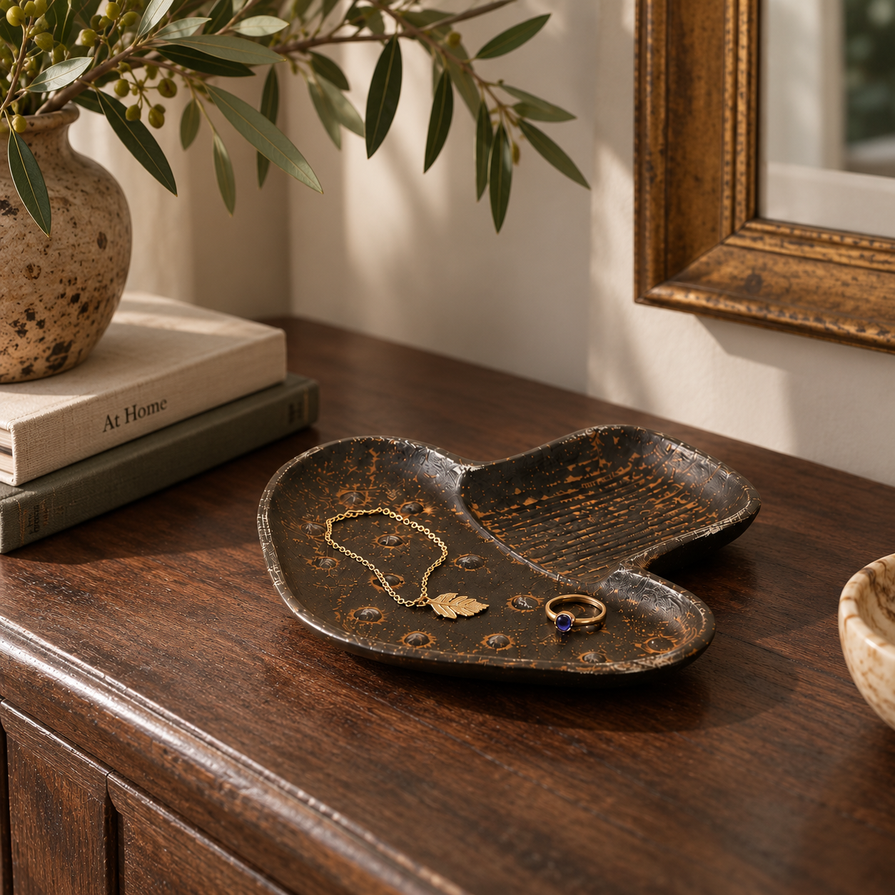 Black and gold cast iron mushroom trinket tray holding jewelry on a wooden table