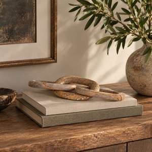Brown marble interlocking links displayed on books on a wooden table