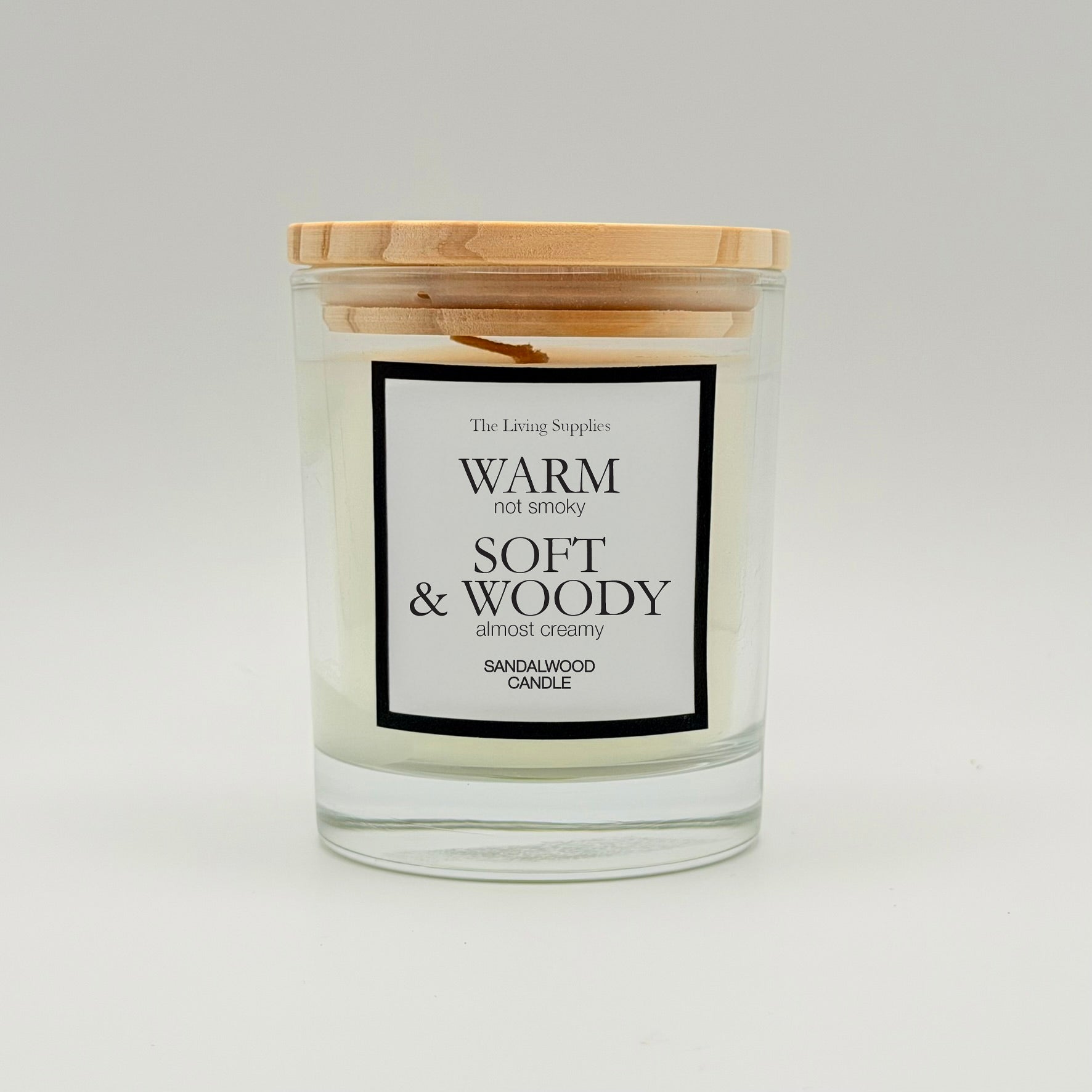 Sandalwood candle in a clear glass jar with a wooden lid and black-bordered label