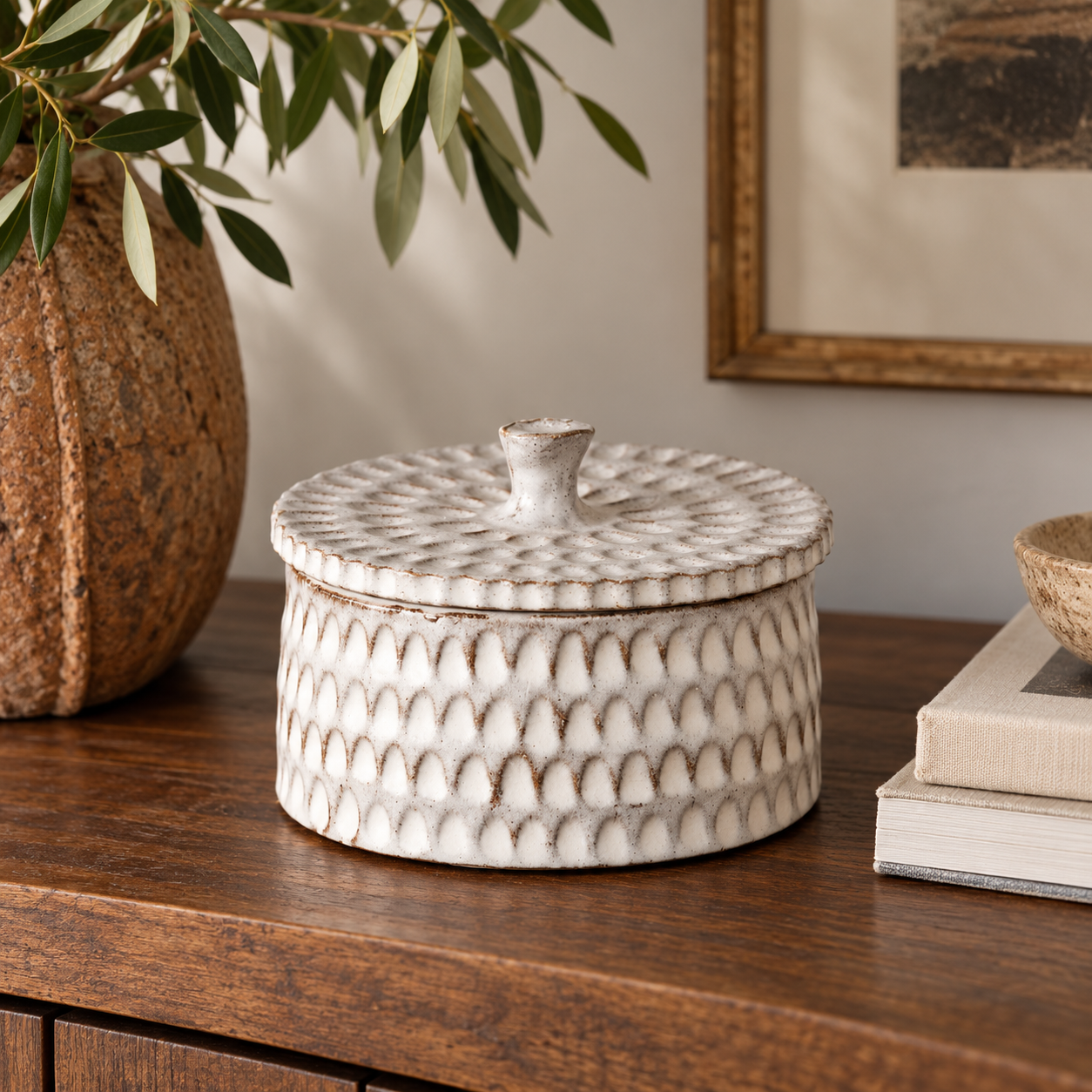 Gray ceramic trinket box with a textured surface and sculptural lid on a wooden table