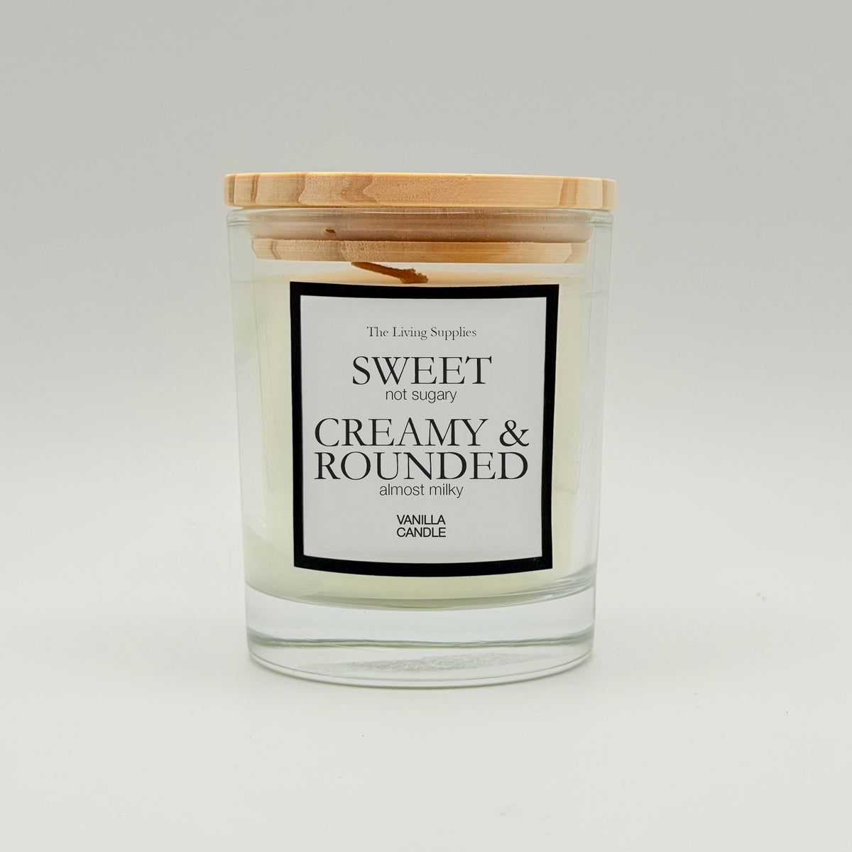 Vanilla candle in a clear glass jar with a wooden lid and black-bordered label