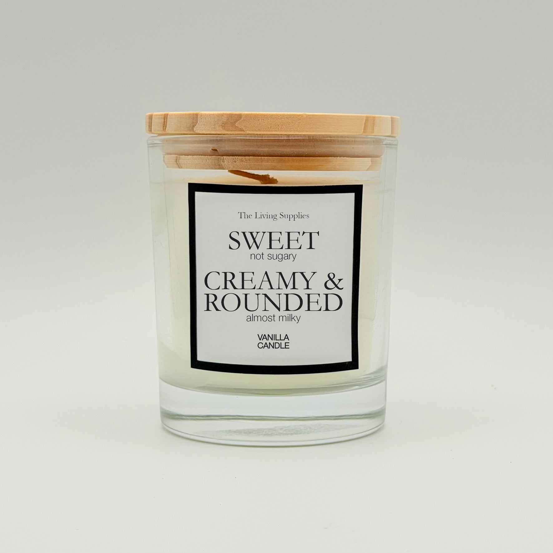 Vanilla candle in a clear glass jar with a wooden lid and black-bordered label