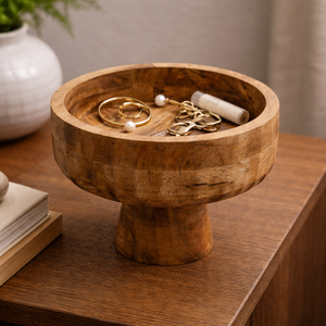 Wooden pedestal bowl holding jewellery on a wooden table